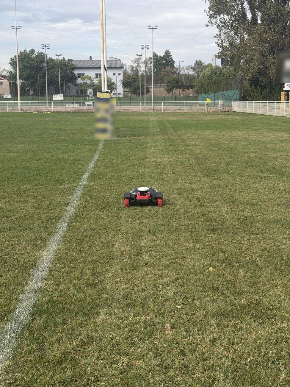 Robot tondeuse Kress RTK près des poteaux d’un terrain de rugby