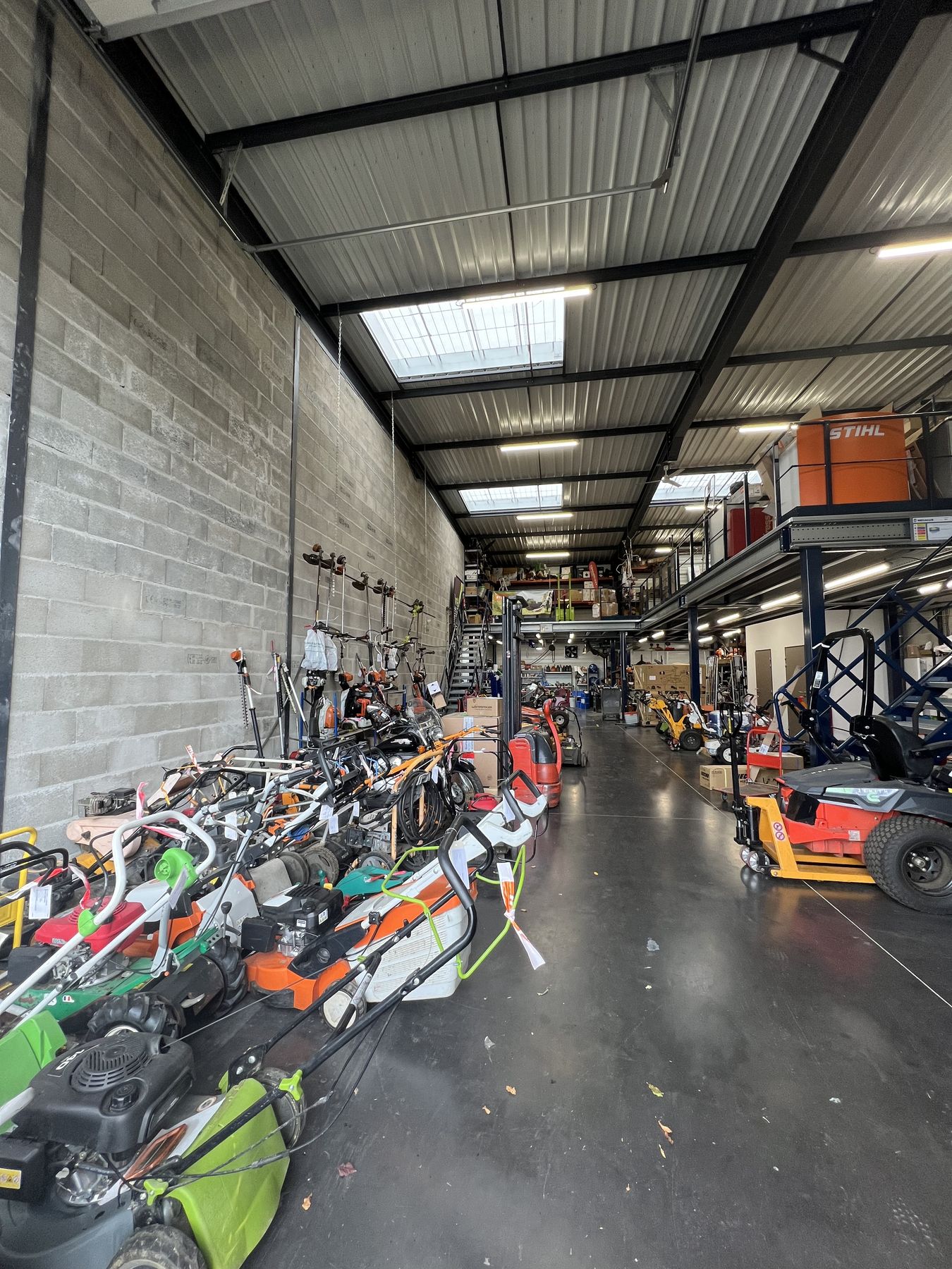 Allée de l’atelier SAV avec tondeuses, débroussailleuses et autoportées